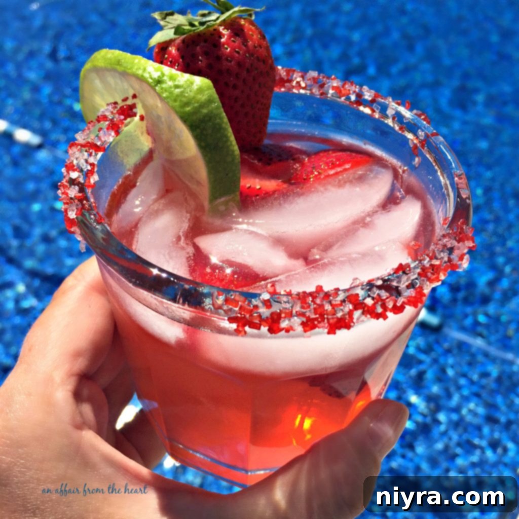 Strawberry Margarita served in a glass with a sugar rim and fresh strawberries
