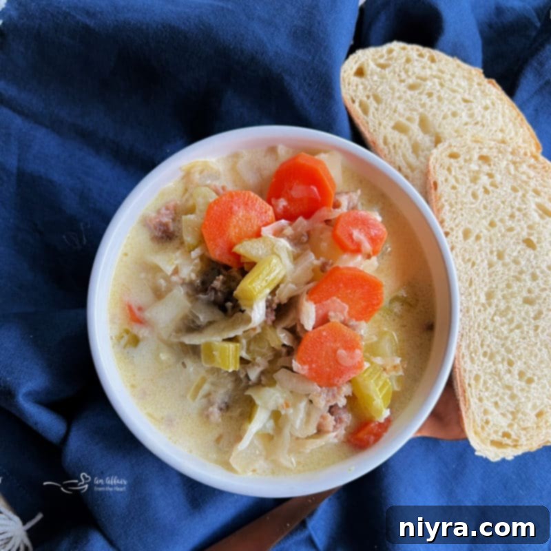 Creamy bowl of authentic sauerkraut soup with golden-brown bratwurst and diced potatoes