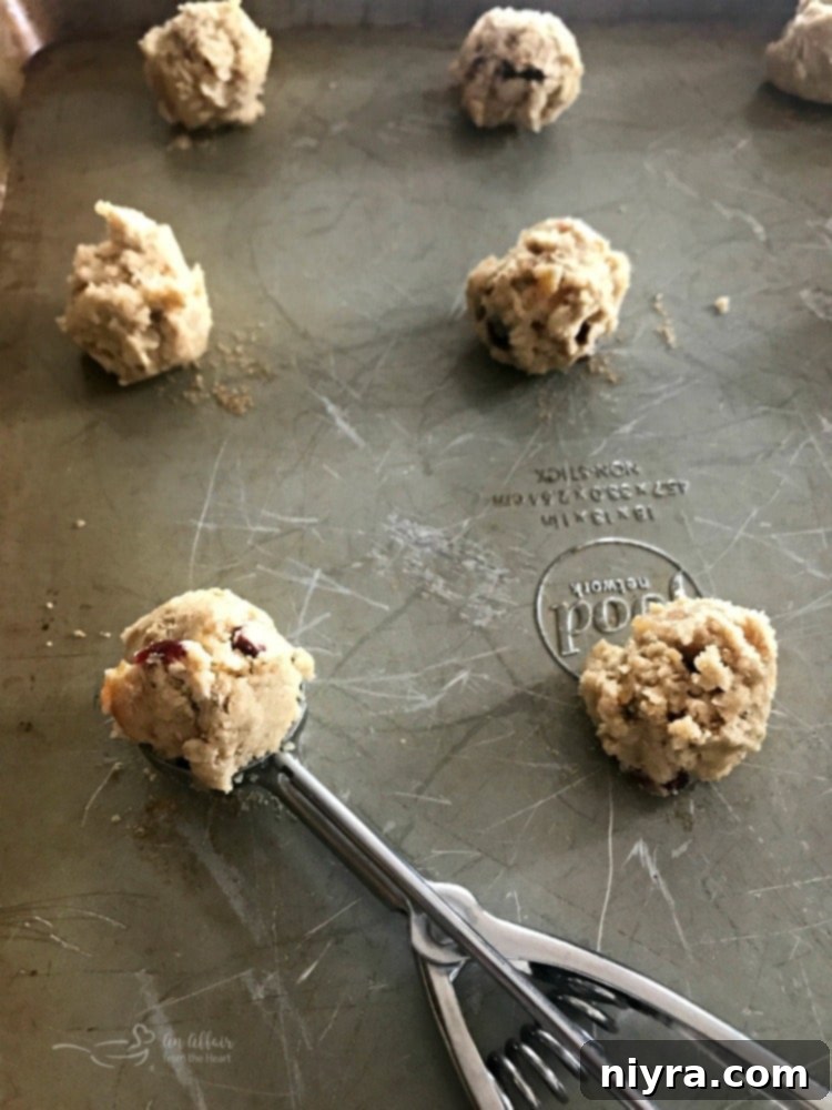 Cookie dough being scooped onto a baking sheet for Cranberry Apricot Oatmeal Cookies