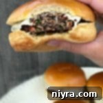 Krautfire Bacon Burger 10 Spicy Bacon Kraut Burger with a bite taken out, showing the layers of ingredients.