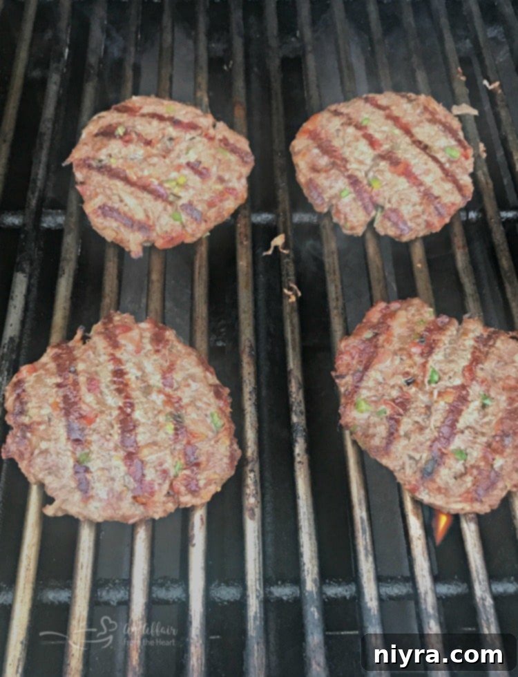 Krautfire Bacon Burger 5 Spicy Bacon Kraut Burgers cooking on the grill, showing a slight char.