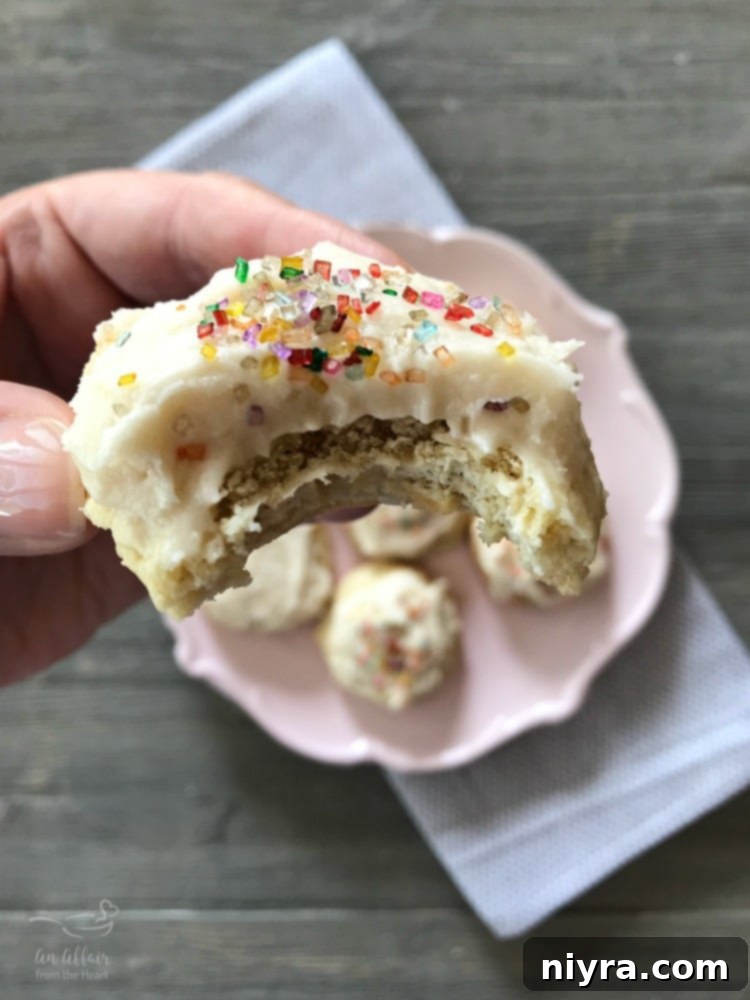 Close-up of a frosted sour cream sugar cookie with a bite taken out, showing its soft interior.
