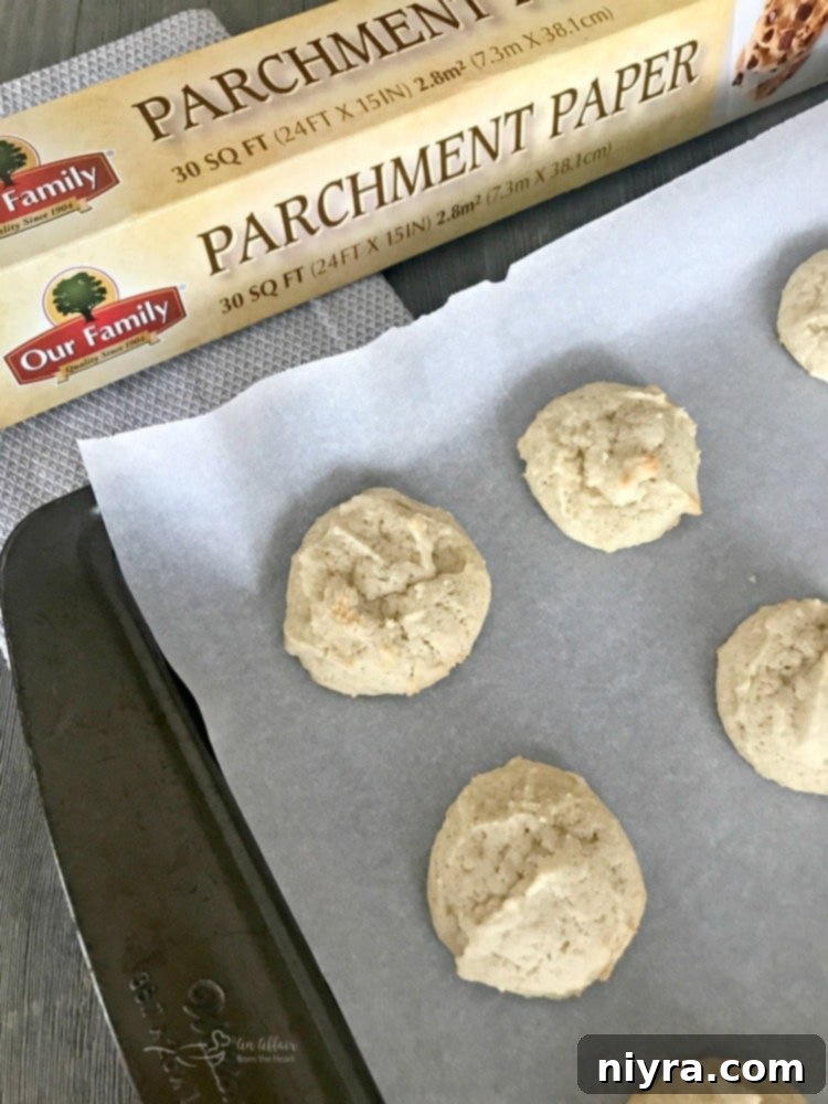 Baked Old Fashioned Frosted Sour Cream Sugar Cookies on parchment paper, cooling.
