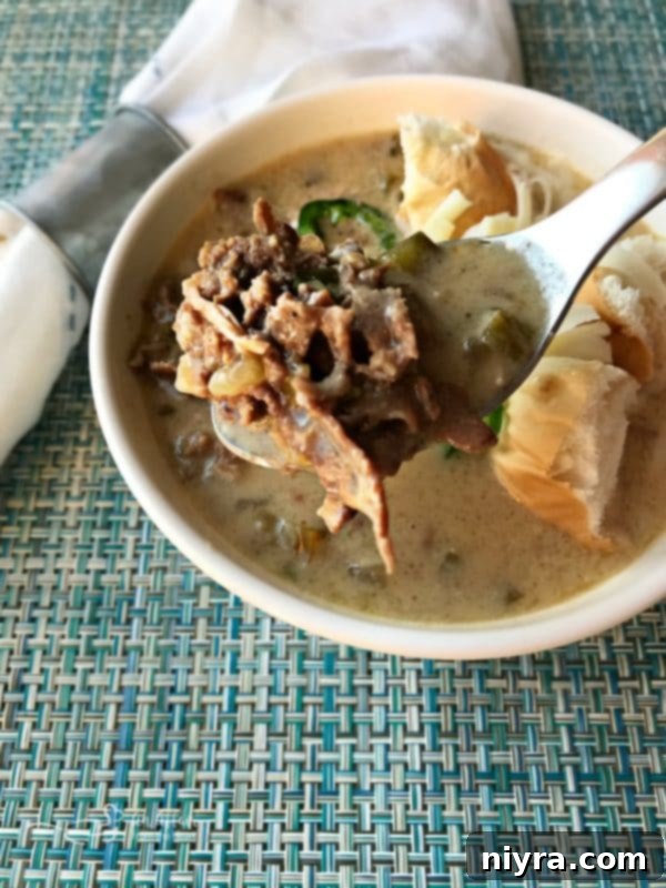 A spoonful of Philly Cheese Steak Soup with melted cheese and steak pieces.