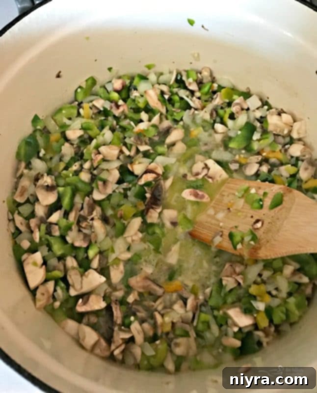 Chopped vegetables (peppers, onions, mushrooms, garlic) sautéing in a Dutch oven.
