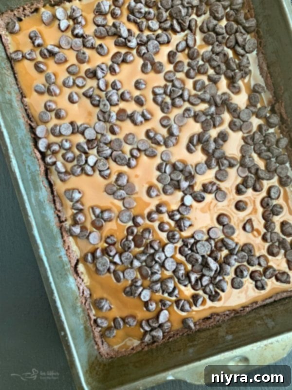 Spreading smooth, gooey caramel over the partially baked chocolate brownie base.