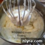 Whipped cream frosting in a mixer with text 'whipped cream frosting'