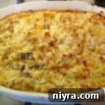 overhead of loaded baked potato casserole, golden brown and bubbly, garnished with fresh chives