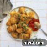 Overhead of Air Fryer Toasted Ravioli with a spoonful of tomato sauce on a white plate.