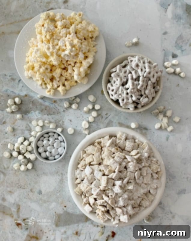 Various components of Winter Wonderland Snack Mix laid out for mixing, including popcorn, Chex, and marshmallows