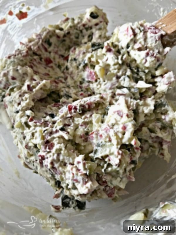 Chopped dill pickles being added to cream cheese