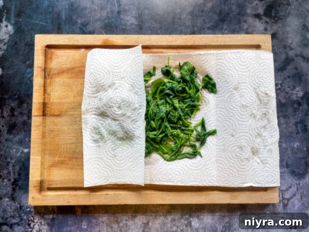 Wilted spinach being pressed to remove excess liquid