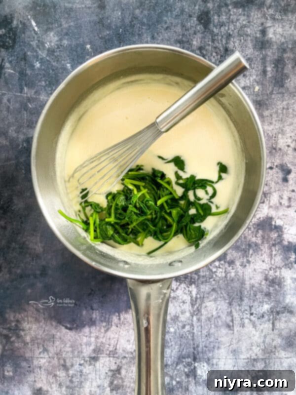 Wilted spinach added to the creamy Alfredo sauce