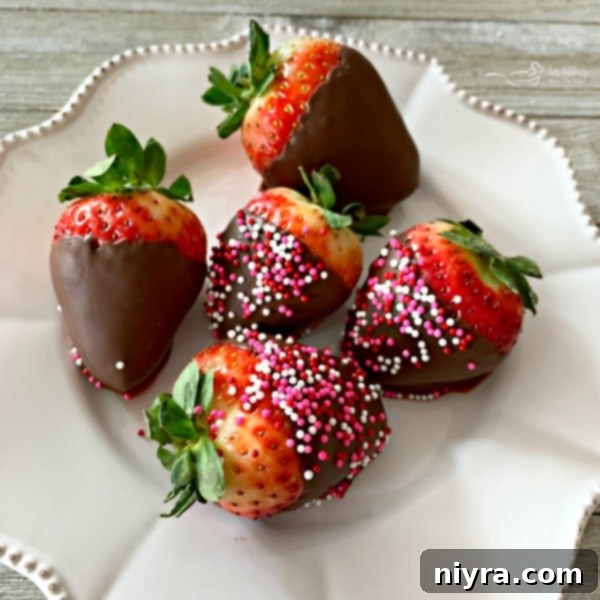 Decadent milk chocolate-covered strawberries, some adorned with festive sprinkles, elegantly prepared for a Valentine's dessert board, highlighting their beautiful presentation.