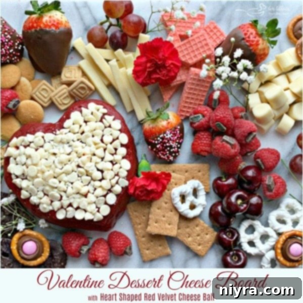 A beautifully arranged Valentine's Dessert Cheese Board featuring a heart-shaped red velvet cheese ball as its centerpiece, surrounded by an assortment of fresh berries, decadent sweet treats, and complementary cheeses.