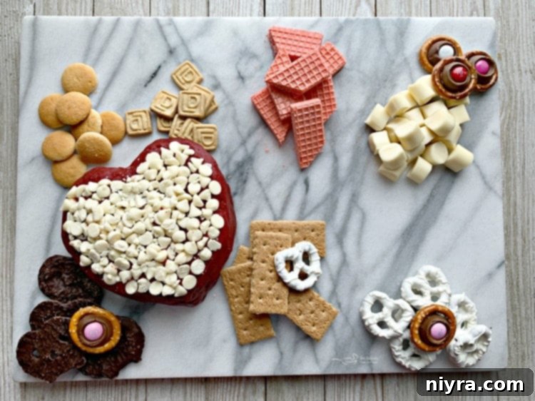 Arranging various sweet dippers like graham crackers, mini shortbread cookies, vanilla wafers, and homemade Rolo pretzels on a Valentine's Dessert Cheese Board.