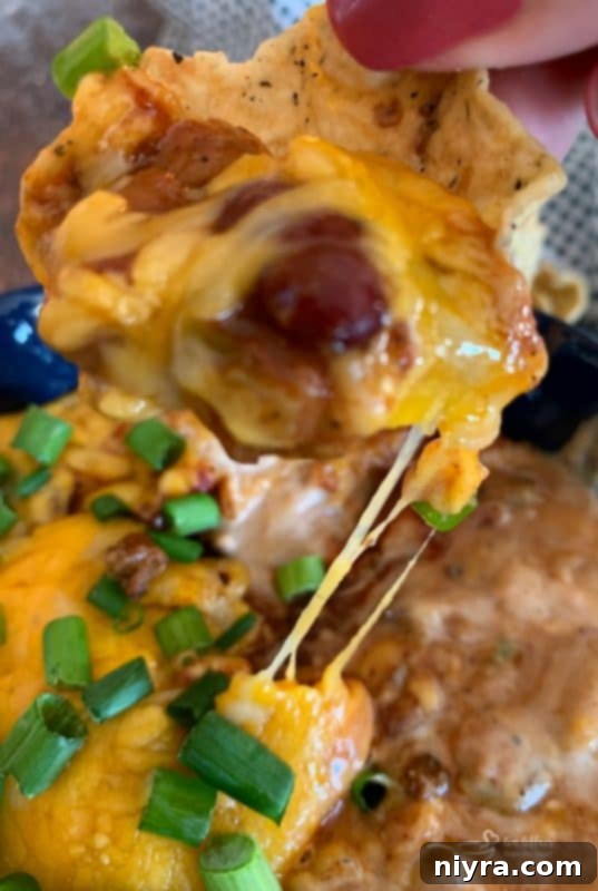 Close-up of Chili Cheese Bean Dip showing a delicious cheese pull as a spoon scoops it out