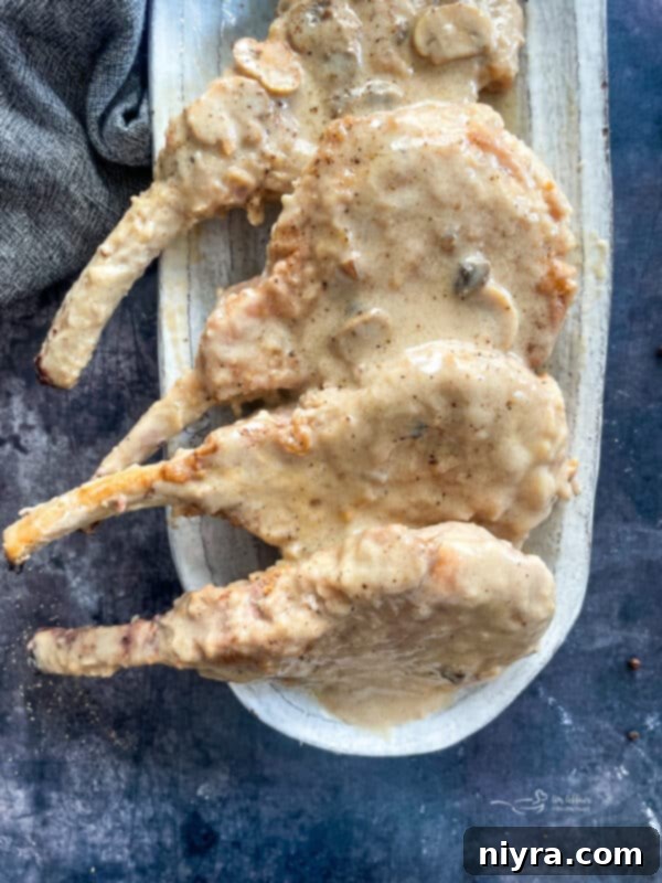 Mantar Soslu Domuz Pirzolası 3 Delicious pork chops simmering in a creamy mushroom gravy, ready to be served.