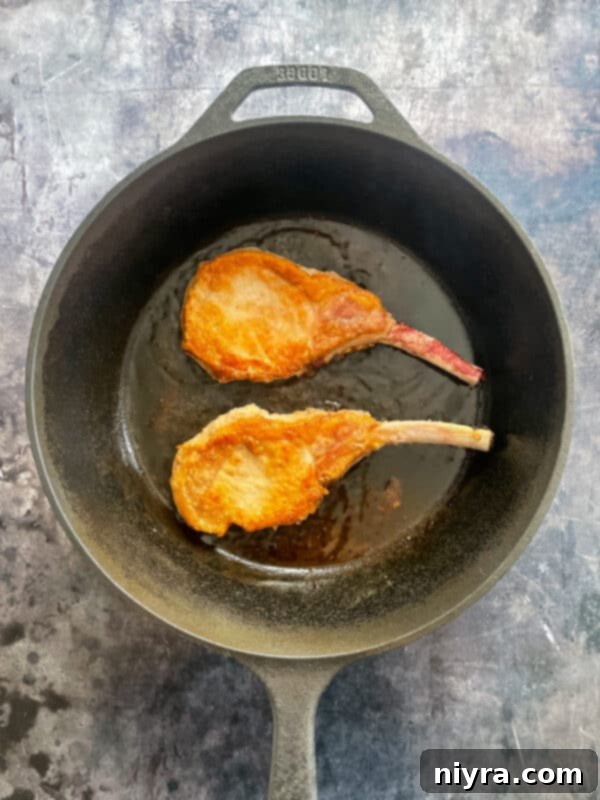 Mantar Soslu Domuz Pirzolası 6 Raw pork chops coated in seasoned flour, ready to be seared in a hot skillet.