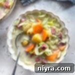 Velvety Corned Beef and Cabbage Soup 17 Creamy Corned Beef & Cabbage Soup in a white scalloped bowl with spoon