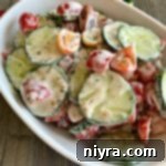 Overhead of Cucumber & Tomato Salad with Yogurt Dressing in a white serving dish
