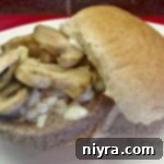 Gourmet Garlic Mushroom Burgers, Simplified 2 Close-up of a Garlic Mushroom Cheeseburger with melted cheese and sautéed mushrooms, highlighting the delicious toppings.