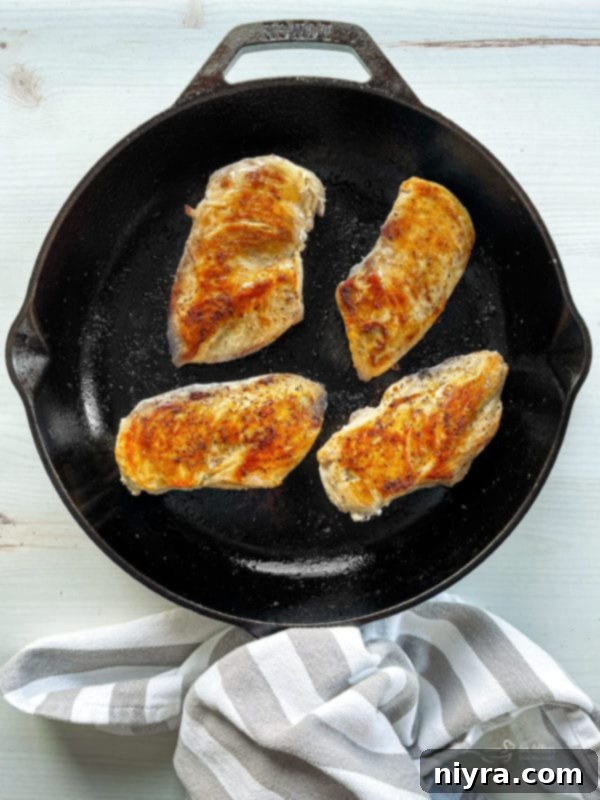 Chicken breasts being sautéed in a pan for Chicken Divan