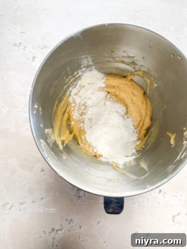 Creamed butter, sugars, eggs, and vanilla in a stand mixer, demonstrating the smooth texture.