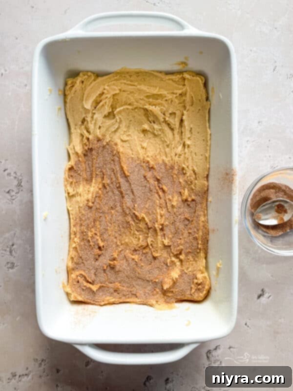 Sprinkling cinnamon-sugar mixture over the first layer of snickerdoodle cookie dough.