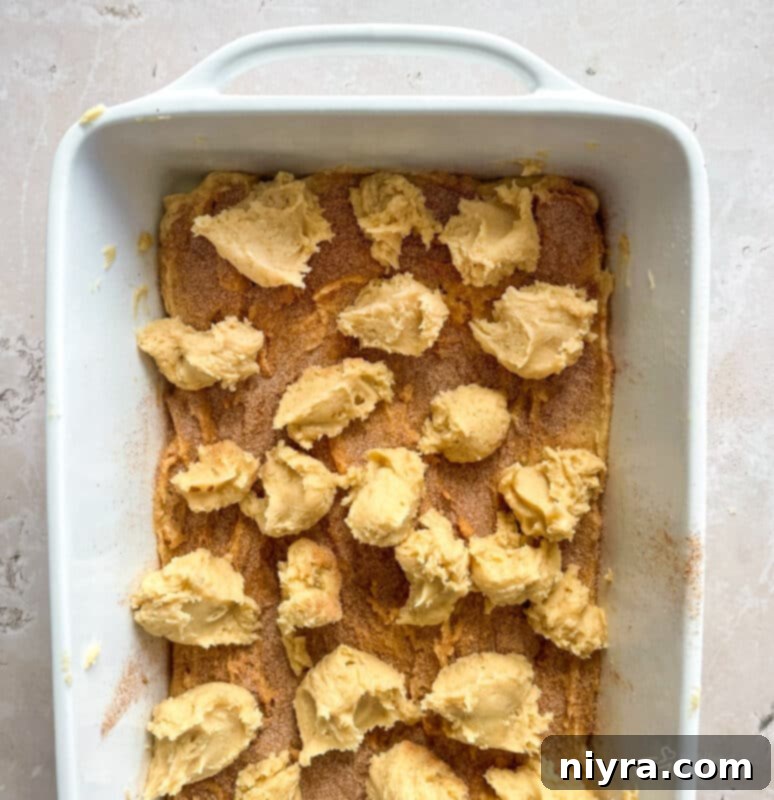 Second half of snickerdoodle cookie dough dolloped over the cinnamon-sugar layer.