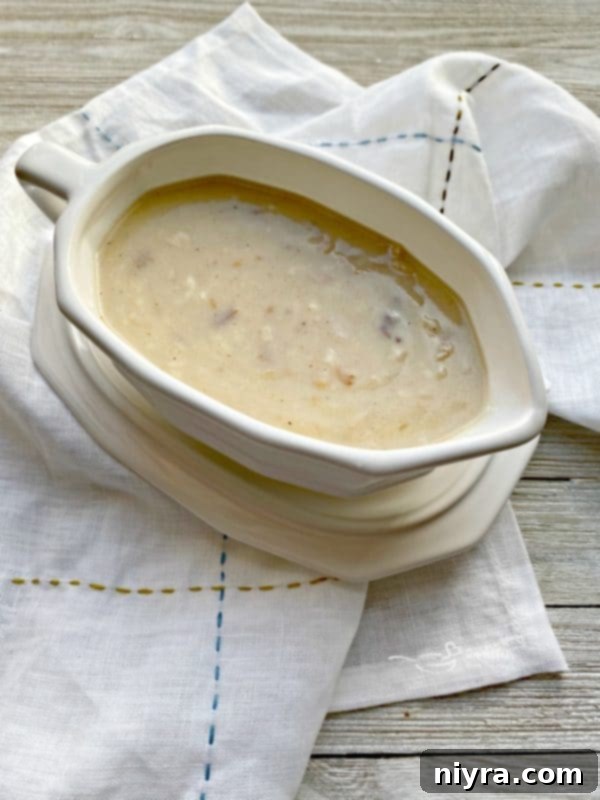 Homemade turkey gravy being poured into a gravy boat, a perfect accompaniment to Thanksgiving dinner