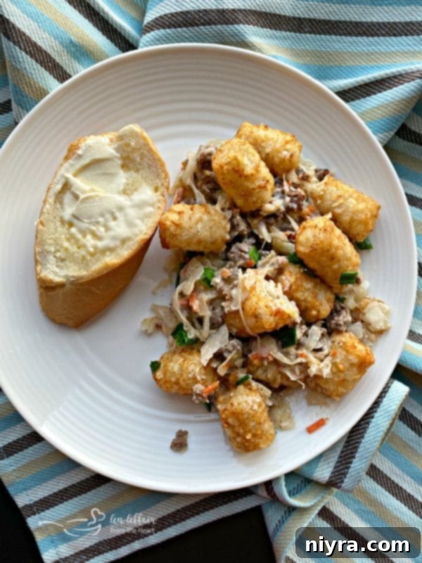 Hearty Beef and Sauerkraut Tater Tot Casserole 8 Close-up of a serving of Beef & Kraut Tater Tot Casserole in a cast iron skillet, garnished with green onions.