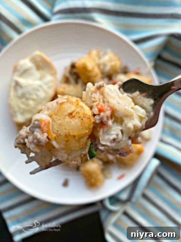 Hearty Beef and Sauerkraut Tater Tot Casserole 9 A spoonful of Beef & Kraut Tater Tot Casserole being scooped out, showing the layers and crispy topping.