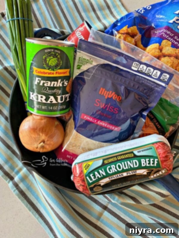 Hearty Beef and Sauerkraut Tater Tot Casserole 5 Ingredients for Beef & Kraut Tater Tot Casserole laid out on a table: ground beef, onion, carrots, Frank's Kraut, cream of celery soup, Swiss cheese, tater tots, scallions.