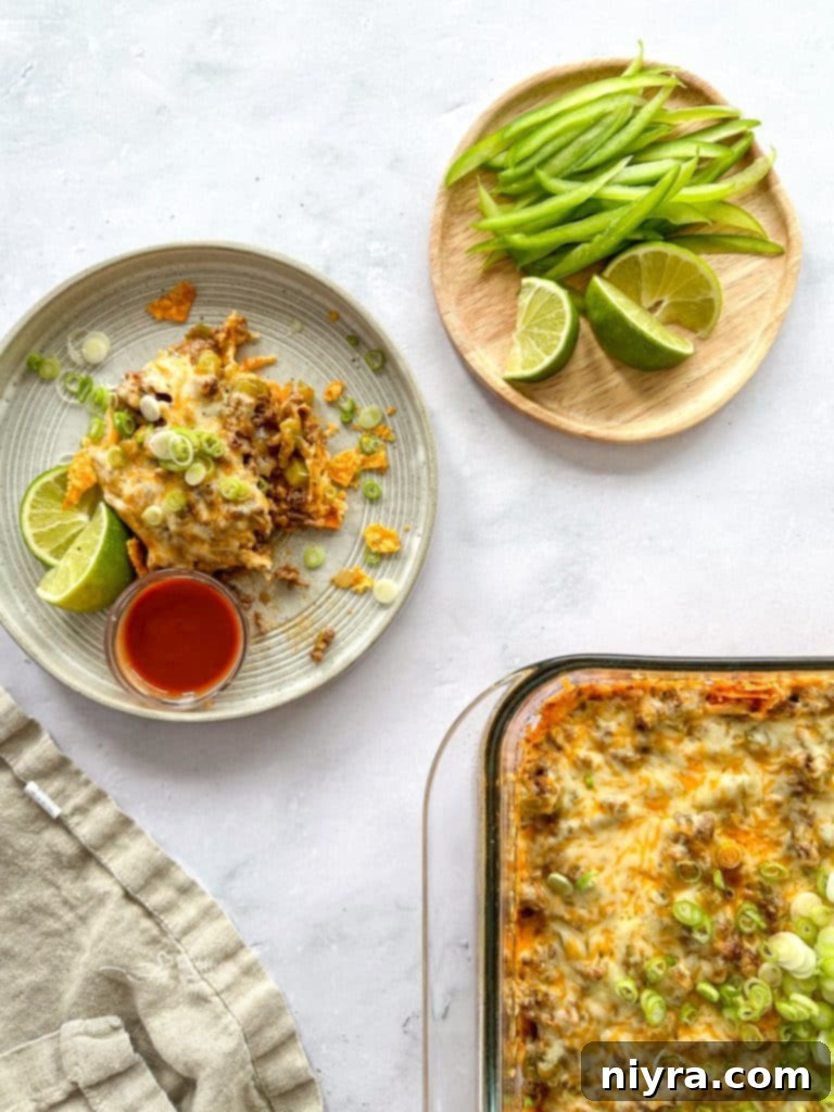 A scoop of Mom's Taco Casserole on a plate with lime wedges and salsa.