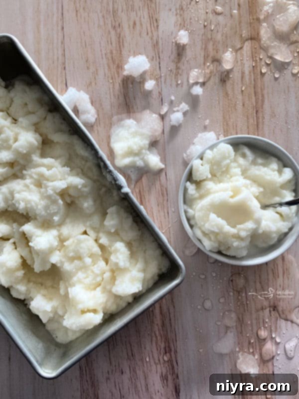 A child's hand holding a bowl of snow ice cream with sprinkles.