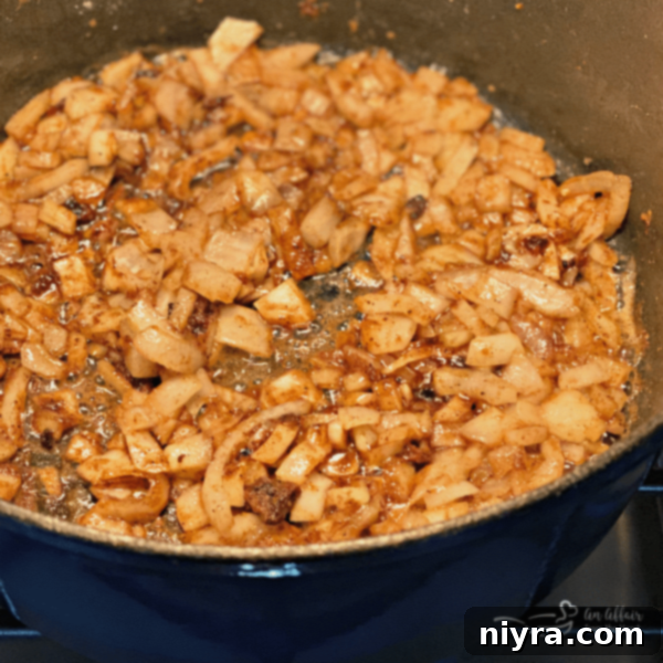 Chopped onions sautéing in a Dutch oven with pan drippings