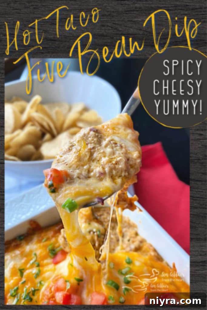 A large serving platter with Hot Taco Five Bean Dip, garnished with diced tomatoes and green onions, surrounded by a generous amount of tortilla chips for dipping.