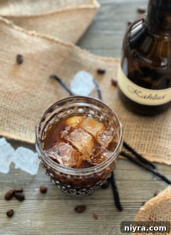Two clear bottles of homemade Kahlua, one with a simple label, against a rustic wooden background.
