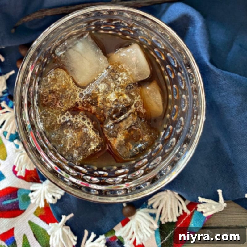 Two glasses of Kahlua on ice, with coffee beans scattered on a wooden surface.