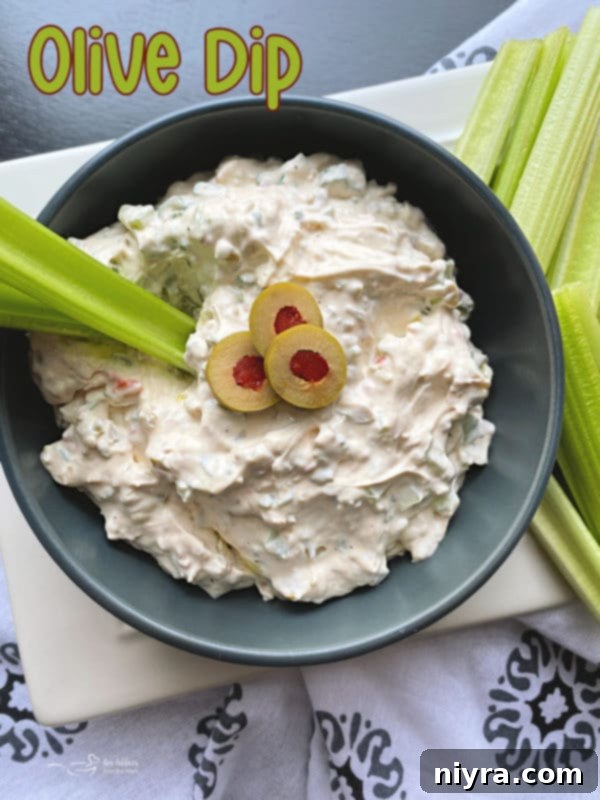 A beautiful bowl of olive dip ready to be scooped, surrounded by fresh ingredients.