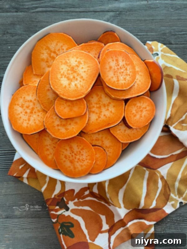 Thinly sliced sweet potatoes ready for seasoning, fanned out on a cutting board.