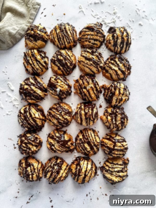 Several chocolate-drizzled coconut macaroons on a white plate