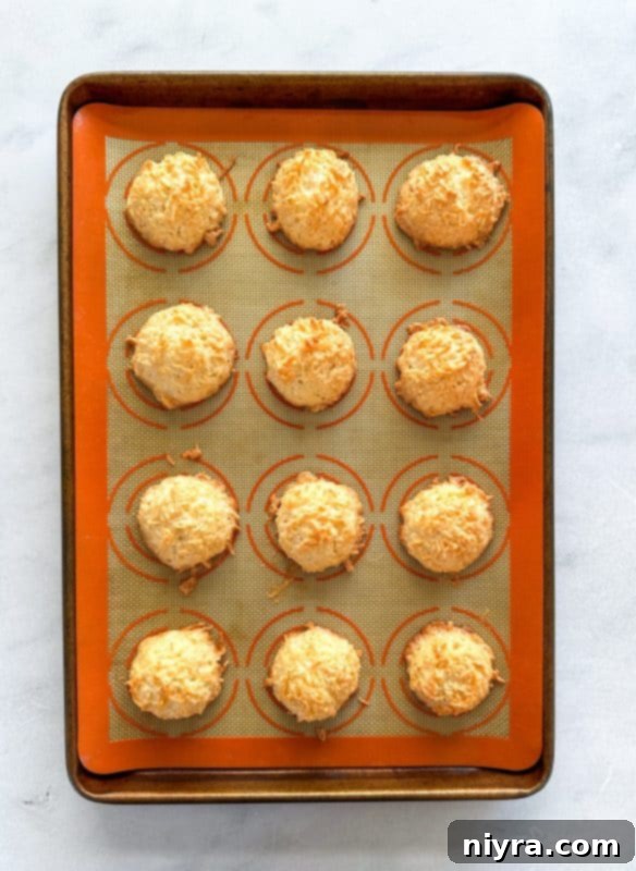 Coconut macaroon mounds evenly spaced on a baking sheet lined with parchment paper