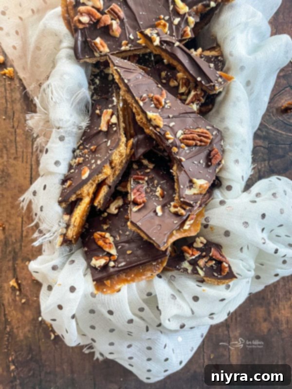 Delicious graham cracker toffee brittle with chocolate and pecans, served on a white cloth.