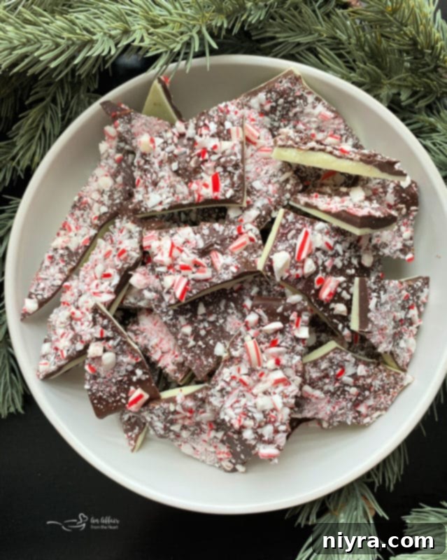 A charming bowl overflowing with homemade white and dark chocolate peppermint bark pieces, highlighting their festive colors.