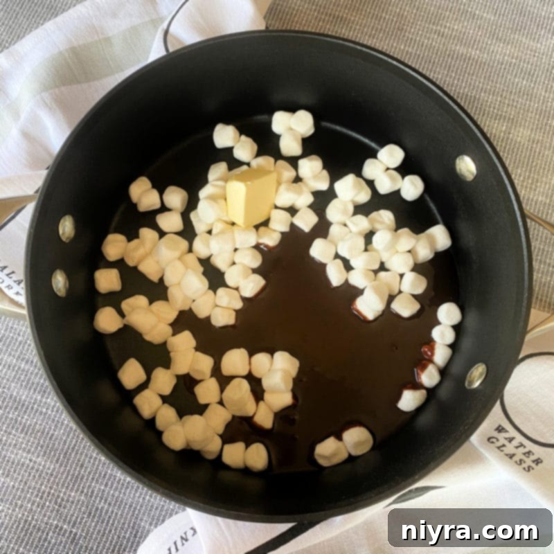 Melting marshmallows, butter, and chocolate syrup in a saucepan