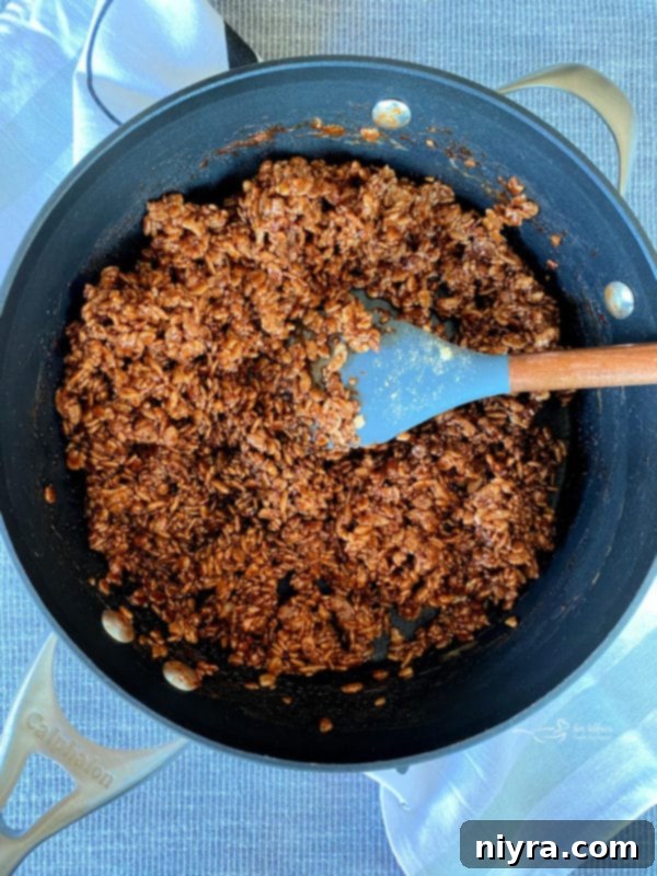Mixing cereal with chocolate marshmallow mixture until fully coated