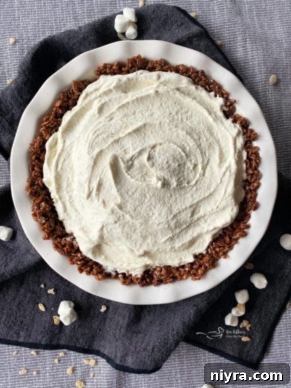 Preparing Chocolate Marshmallow Pie Crust with vanilla ice cream in a white pie plate