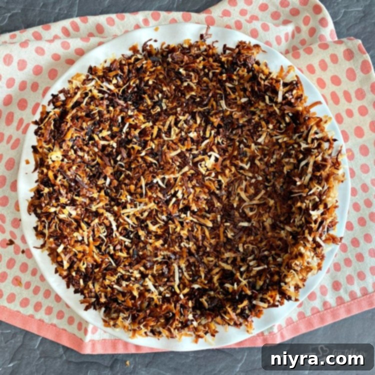 Pressing toasted coconut into a pie plate to form a crust